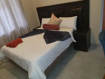 a bed with white sheets and pillows with a purse on it at Mabel Guesthouse in Cape Town