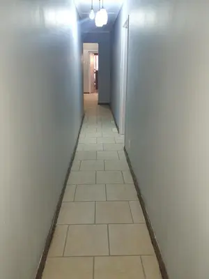a hallway with a tile floor and white walls at Mabel Guesthouse in Cape Town