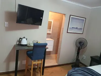 a bedroom with a desk with a television on the wall at Mabel Guesthouse in Cape Town