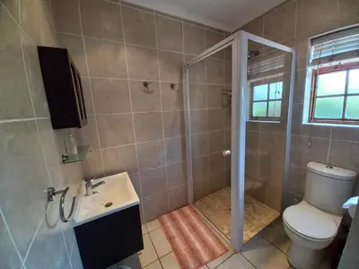 a bathroom with a shower and a toilet and a sink at Wine Route 44 Guesthouse in Somerset West