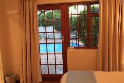 a bedroom with a window with a view of a pool at Wine Route 44 Guesthouse in Somerset West