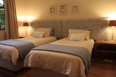 two beds in a hotel room with two lamps at Wine Route 44 Guesthouse in Somerset West