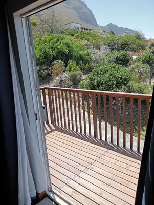 a door to a deck with a view of a mountain at Aloe Ocean Flatlet in Bettyʼs Bay
