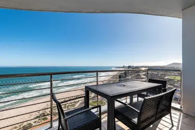 a table and chairs on a balcony with the beach at Horizon Bay 1502 in Cape Town
