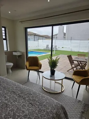 a bedroom with a bed and a table and chairs at LND GUEST HOUSE in Bloubergstrand