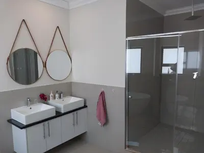 a bathroom with two sinks and a shower and mirrors at LND GUEST HOUSE in Bloubergstrand