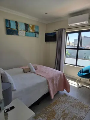 a bedroom with a bed and a large window at LND GUEST HOUSE in Bloubergstrand