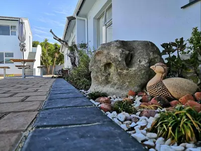 a garden with two ducks sitting on a rock at Southeaster in Bloubergstrand