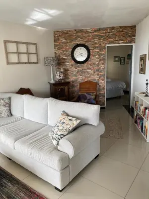 a living room with a couch and a clock on a brick wall at Seaview Sunset Boutique Apartments Gordonsbay Solar powered in Cape Town