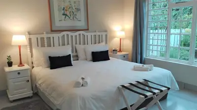 a bedroom with a large white bed with two lamps at Seashell Cottage in Hermanus