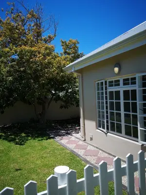 a white fence in front of a house at Seashell Cottage in Hermanus