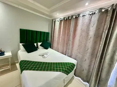 a bedroom with a large bed with a green headboard at Mowetu Guest House in Cape Town