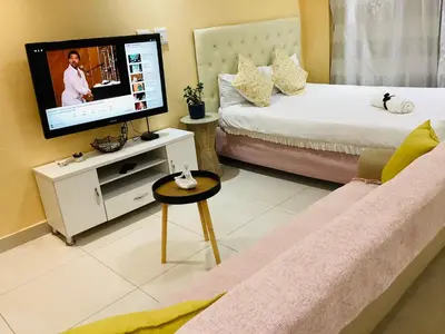 a living room with a couch and a tv on a wall at Mowetu Guest House in Cape Town