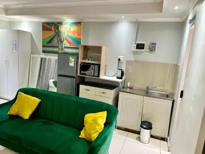a living room with a green couch and a kitchen at Mowetu Guest House in Cape Town