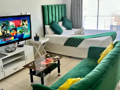 a bedroom with a bed and a tv and a couch at Mowetu Guest House in Cape Town