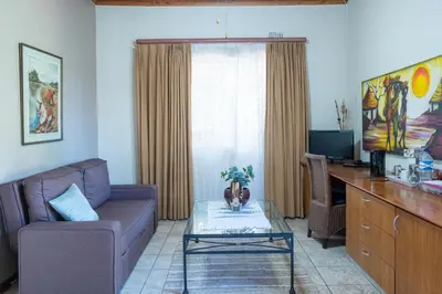 a living room with a couch and a desk at The Sanctuary Guest House Estate in Cape Town