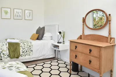 a bedroom with a bed and a dresser and a mirror at Fernkloof Cottage in Hermanus