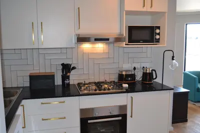 a kitchen with white cabinets and a stove top oven at Shore2Please in Cape Town