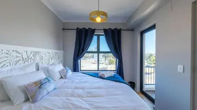 a bedroom with a bed with a large window at Shore2Please in Cape Town