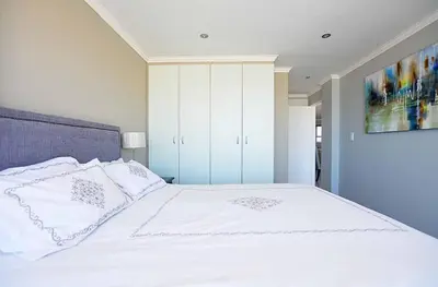 a bedroom with a large bed with white sheets and pillows at Nautica 2 Bedroom Beachfront Apartment with Sea Views in Bloubergstrand