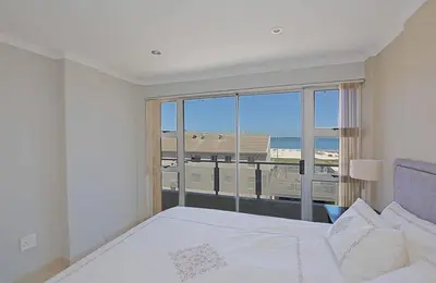 a bedroom with a bed and a view of the beach at Nautica 2 Bedroom Beachfront Apartment with Sea Views in Bloubergstrand