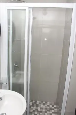 a shower with a glass door next to a sink at The White House Lodge in Cape Town