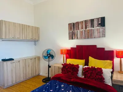 a bedroom with a bed with red and yellow pillows at Peaceful getaway in Cape Town
