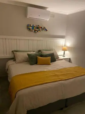 a bedroom with a large bed with a yellow blanket at Huis by die See in Hermanus