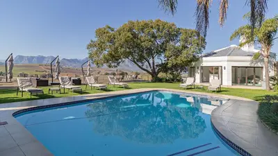 a swimming pool with chairs and a house at The Salene Hotel & Apartments in Stellenbosch