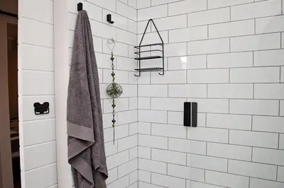 a white tiled shower with a towel hanging on it at Aloe Aloe Cottage in Cape Town