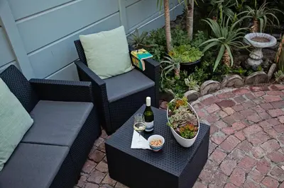a table with a bottle of wine and a bowl of food at Aloe Aloe Cottage in Cape Town