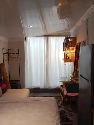 a bedroom with two beds and a refrigerator and a window at Cozy Private En Suite Studio in Cape Town