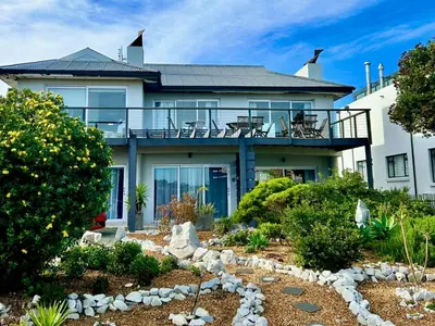 a house with a balcony and a garden at 82 Steps to the Beach in Pringle Bay