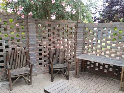 two chairs and a table and a bench in front of a brick wall at TERRA NOVA ACCOMMODATION - Unit Esmé in Cape Town