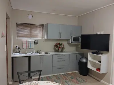 a kitchen with white cabinets and a flat screen tv at TERRA NOVA ACCOMMODATION - Unit Esmé in Cape Town