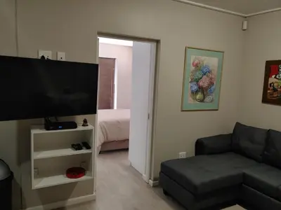 a living room with a couch and a flat screen tv at TERRA NOVA ACCOMMODATION - Unit Esmé in Cape Town
