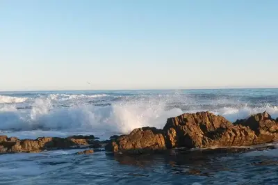 a wave crashing on rocks in the ocean at C'estÇa Cottage Modern Luxurious Sounds of the Sea in Hermanus