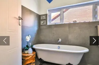 a bathroom with a white tub and a window at In die Hoekie in Hermanus