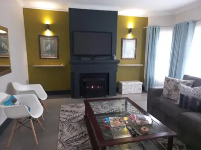 a living room with a fireplace and a tv at In die Hoekie in Hermanus