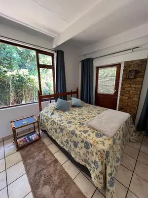 a bedroom with a bed and a window at Santika Garden Cottage Stellenbosch in Stellenbosch