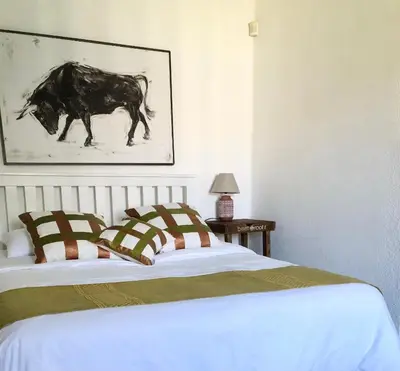 a bedroom with a bed and a picture of a cow at Bird Song Cottage - Table View in Cape Town