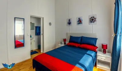 a bedroom with a blue and red bed and a mirror at Glenley place in Hermanus
