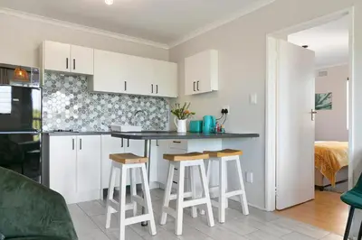 a kitchen with white cabinets and bar stools at Serengeti selfcatering apartments Perfect Stay in Bellville