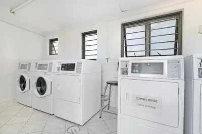 a laundry room with white washing machines and a stool at Serengeti selfcatering apartments Perfect Stay in Bellville