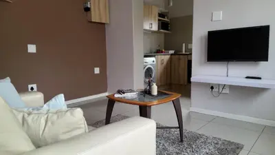 a living room with a table and a tv at Limbila House in Cape Town