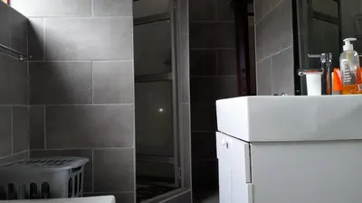 a bathroom with a shower and a white sink at Limbila House in Cape Town