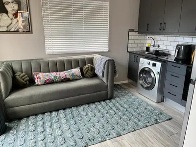 a couch in a kitchen with a washing machine at Marbella - Cozy studio in Heart of Table View in Cape Town