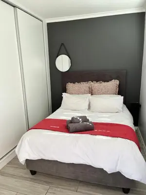 a bedroom with a bed with a teddy bear on it at Marbella - Cozy studio in Heart of Table View in Cape Town