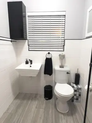 a white bathroom with a toilet and a sink at Marbella - Cozy studio in Heart of Table View in Cape Town