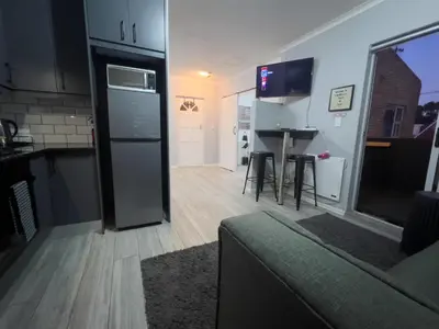 a kitchen and living room with a refrigerator and a table at Marbella - Cozy studio in Heart of Table View in Cape Town